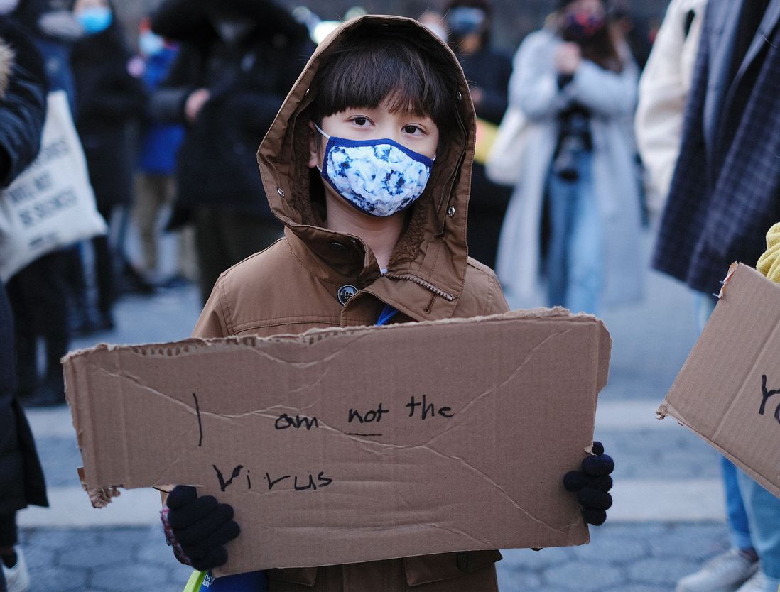 A boy holds a sign that says, "I am not a virus"